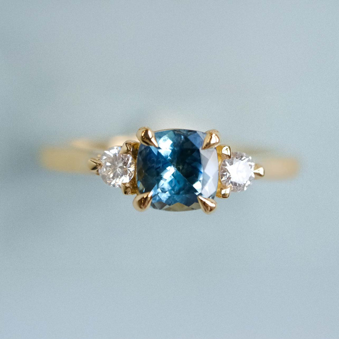 E.C.One STELLA Cushion Teal Sapphire and Diamond Yellow Gold Trilogy Engagement Ring made in our B Corp London workshop